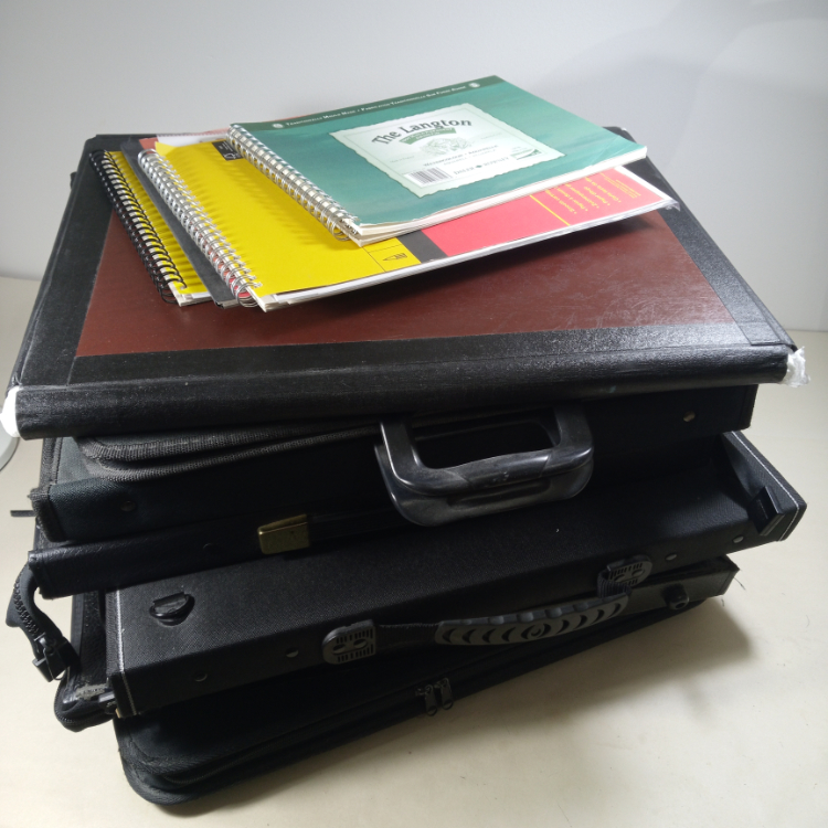 Photo of a pile of portfolios and sketchbooks indicating ways to overcome creative block