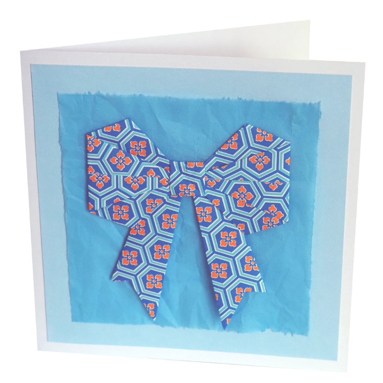 Photograph of greeting card with blue origami bow and blue tissue paper background