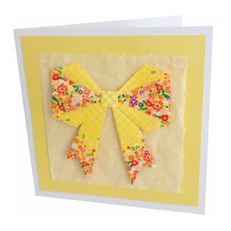 Photograph of greeting card with yellow origami bow and yellow tissue paper background